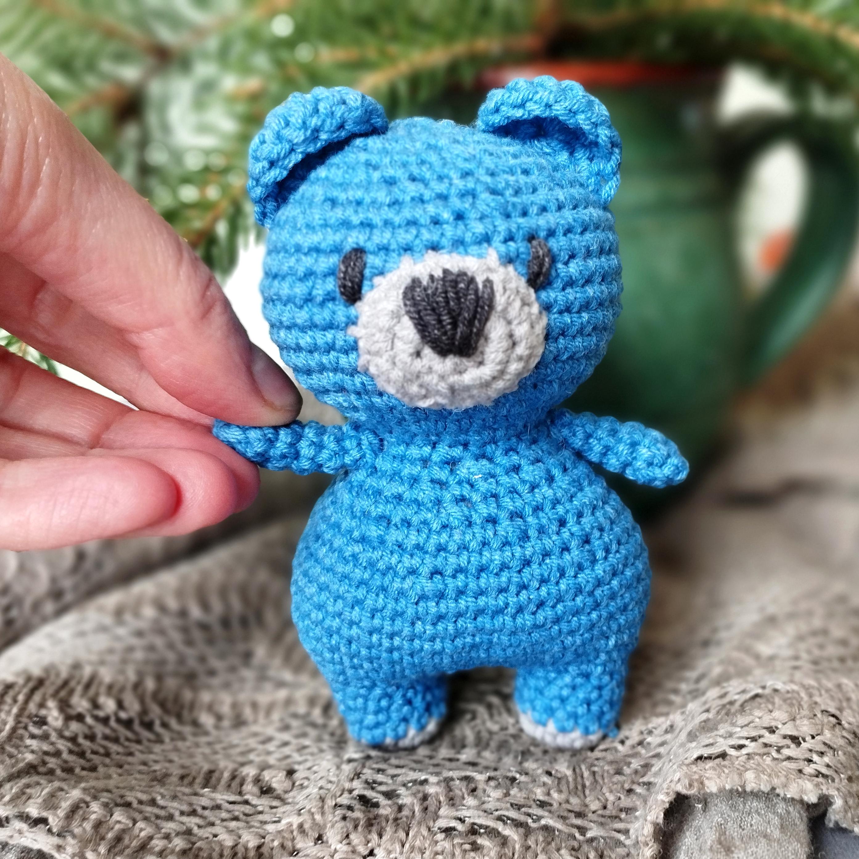 a crocheted blue teddy bear sitting on top of a table